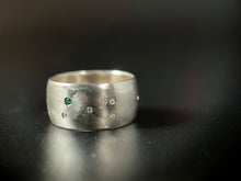 Load image into Gallery viewer, A sterling silver ring with a random scattering of flush set white moissanite stones and a single flush-set emerald.
