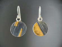 Load image into Gallery viewer, On this side the earrings are made of darkened, oxidized silver with a lined texture. The earring on the left is nearly one half gold, along a slanted line. The other has two tabs of gold reaching towards the center from the top and bottom.
